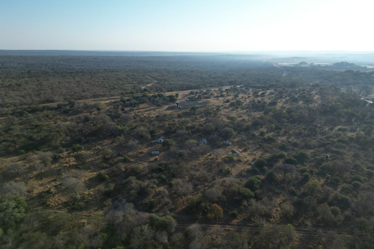An aerial view of a large rural farm property featuring multiple structures set within a vast, natural landscape.