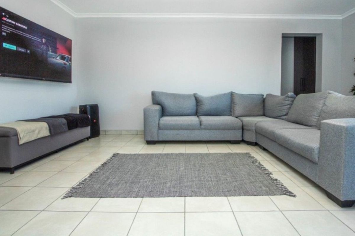 A spacious living room featuring neutral tiled flooring and coved ceilings, providing a clean and functional base for interior design.