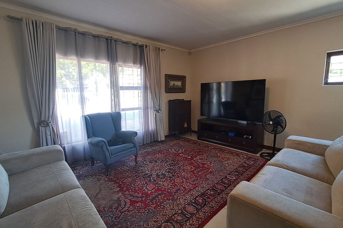 A comfortable living room featuring large windows for natural light, neutral wall tones, and classic coving detail.