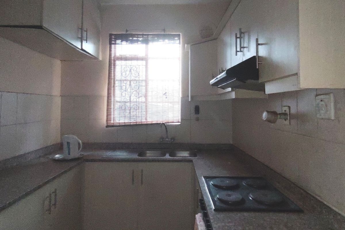 A compact kitchen featuring built-in cabinetry, a double sink, an electric hob with an extractor fan, and tiled backsplashes.