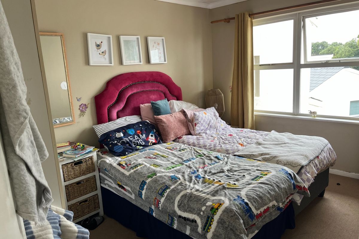 A standard bedroom featuring carpet flooring and a large window, providing natural light and a view of the surrounding area.