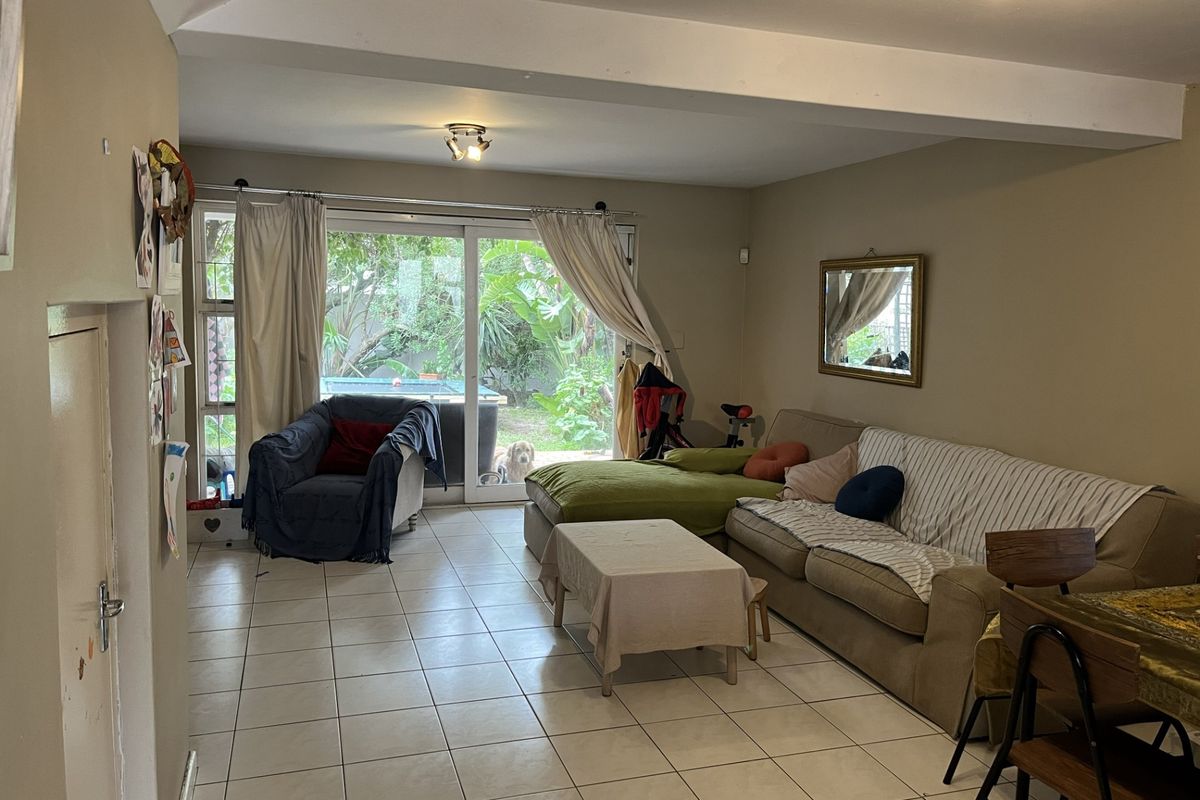 Spacious living area featuring neutral tiled flooring and large sliding glass doors that provide natural light and access to the garden.