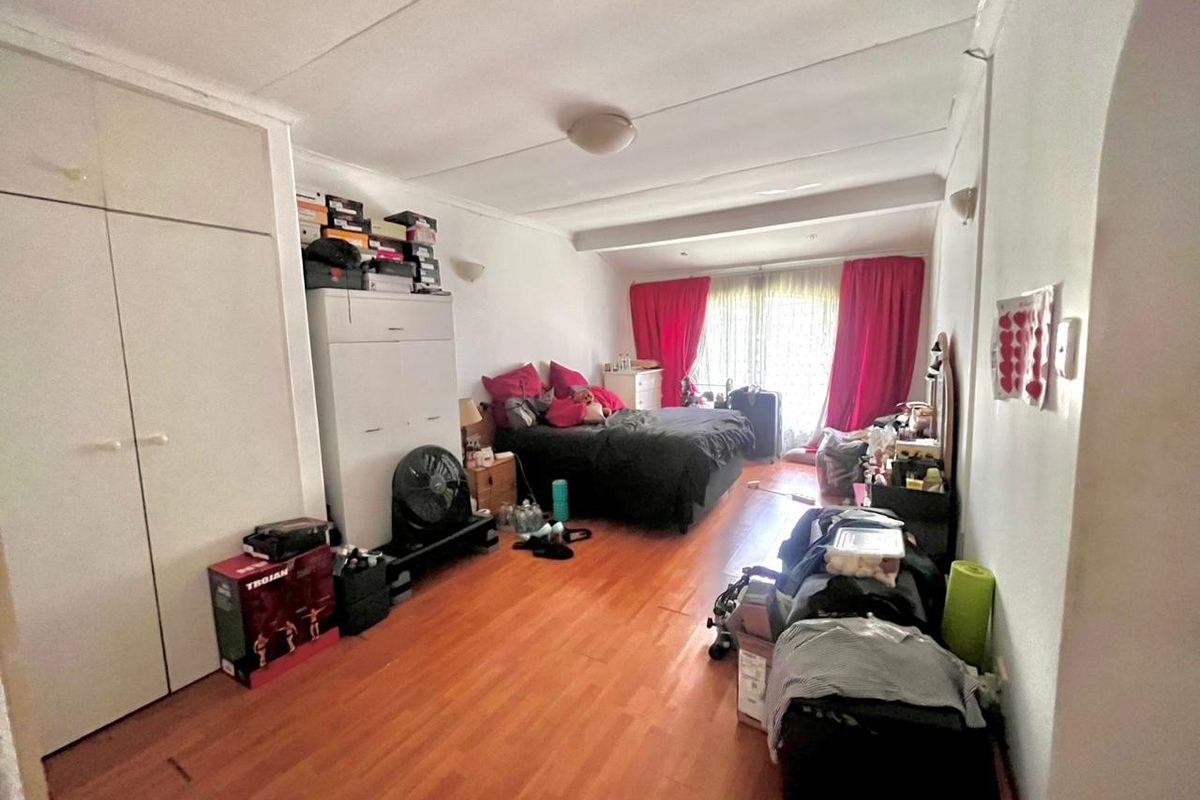 A spacious bedroom featuring laminate flooring and built-in cupboards, offering a functional layout with natural light from the window.