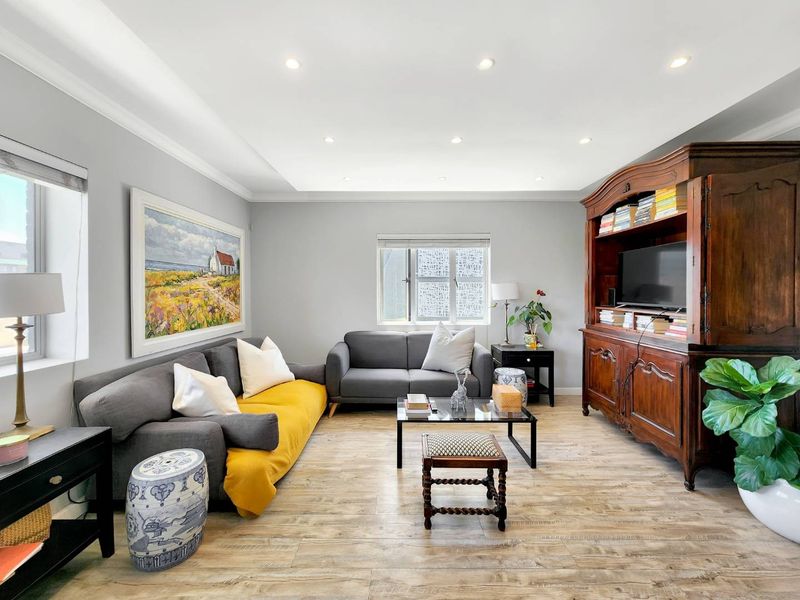 A well-maintained living room featuring wood-look tile flooring, recessed downlighting, and neutral wall finishes.