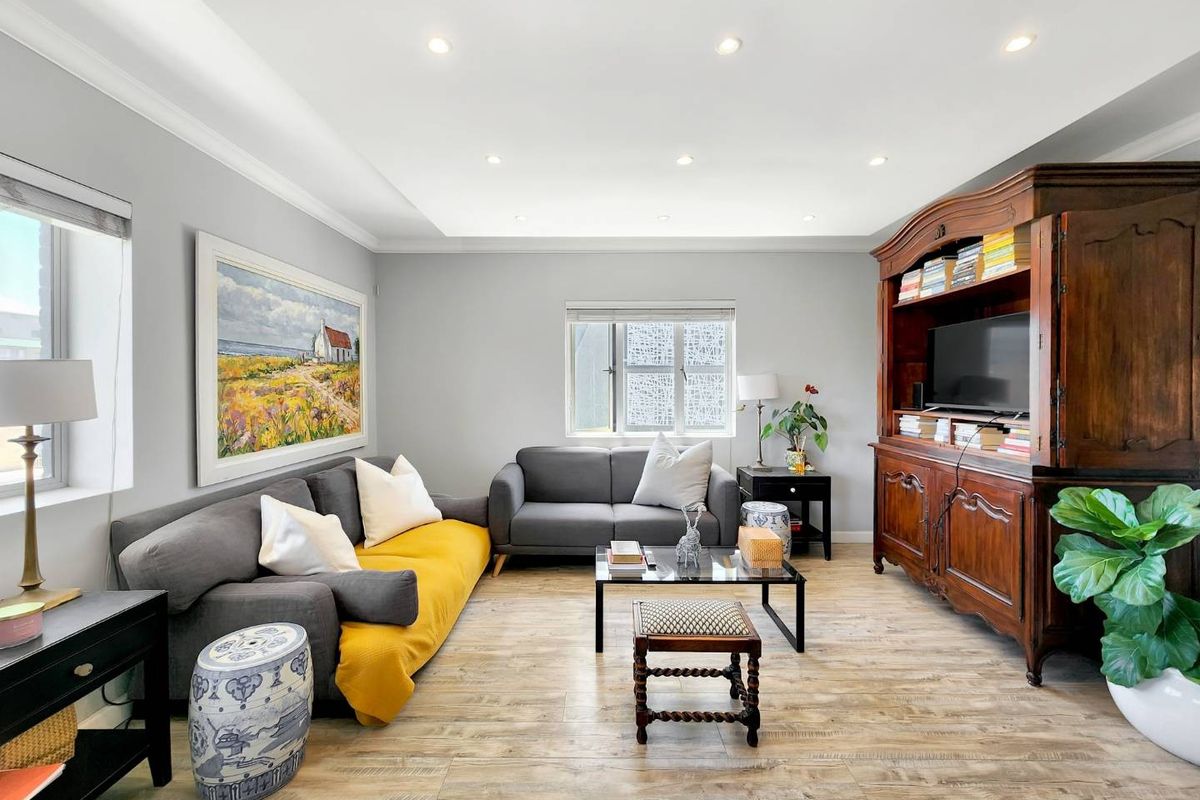 A well-maintained living room featuring wood-look tile flooring, recessed downlighting, and neutral wall finishes.