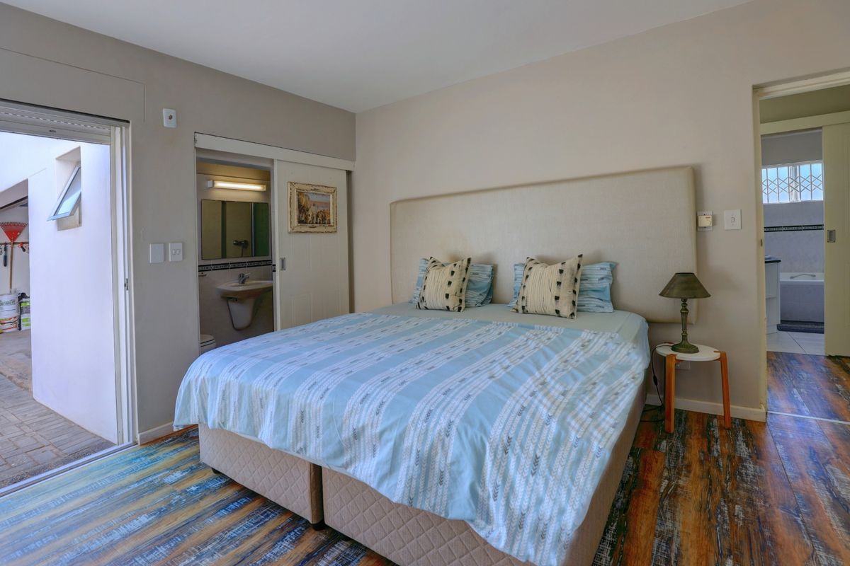 Bedroom featuring a built-in headboard, en-suite bathroom access, and direct access to an outdoor patio area.