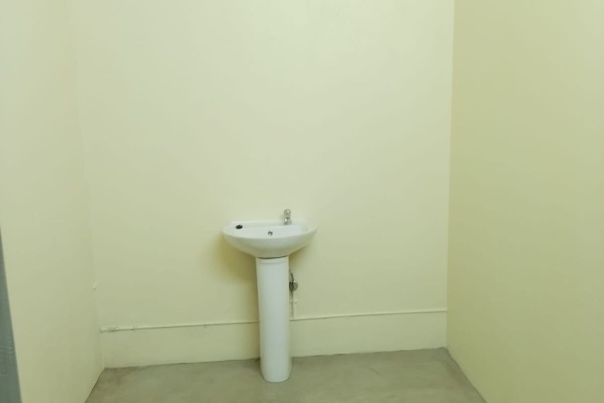 A simple, empty utility room featuring a white pedestal basin and concrete flooring, suitable for use as a basic washroom or utility space.