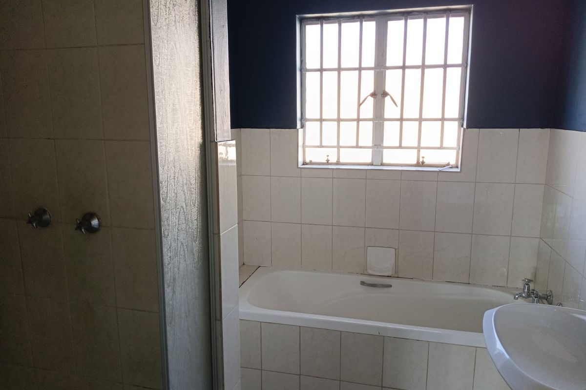 A functional bathroom featuring a built-in bathtub, separate shower enclosure, and pedestal basin with tiled finishes.