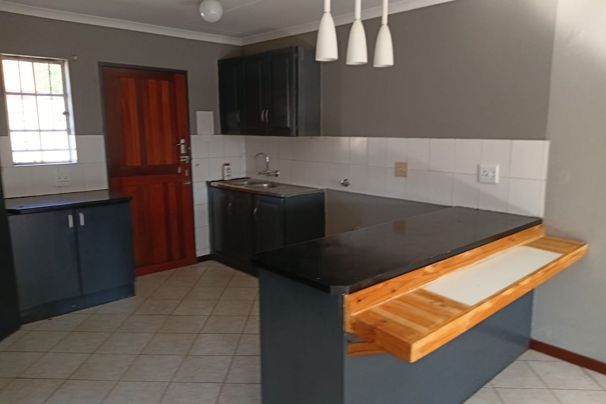 A functional kitchen featuring dark cabinetry, a breakfast bar, tiled splashbacks, and tiled flooring, offering a clean and practical workspace.