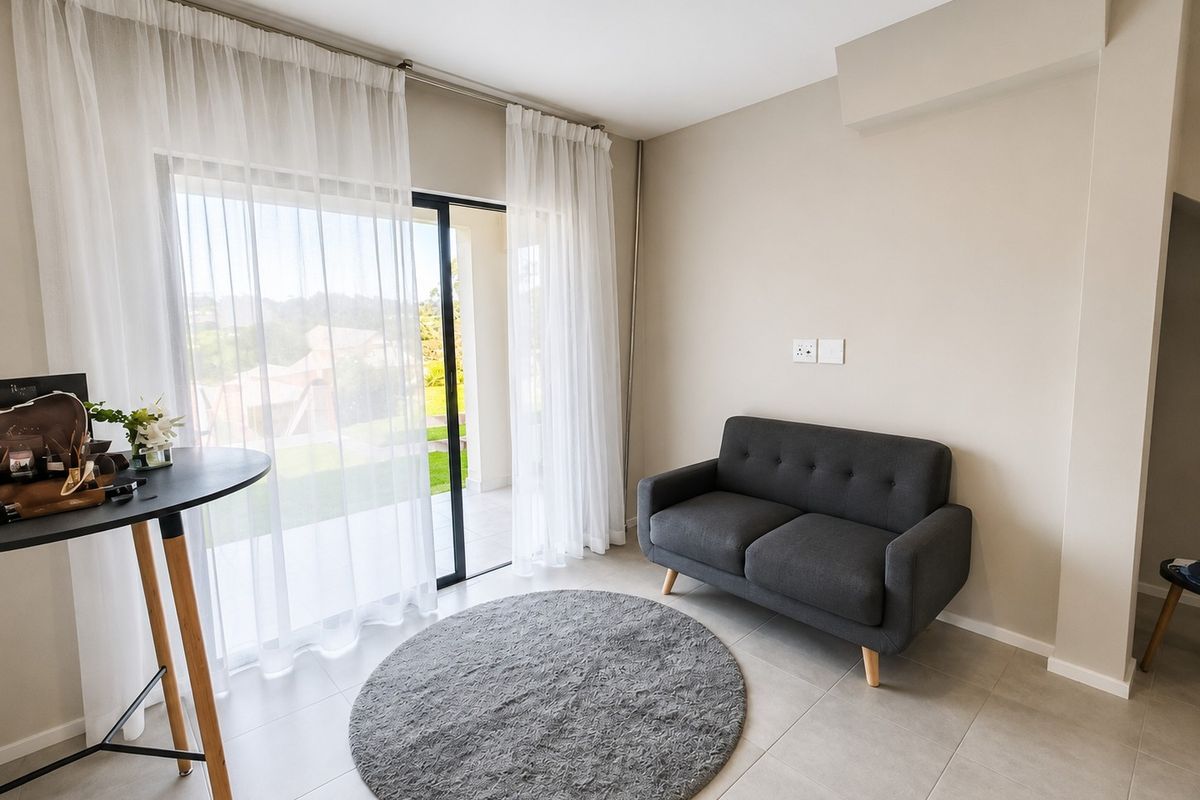 A bright living area featuring tiled flooring and a large sliding glass door that provides access to an outdoor patio space.