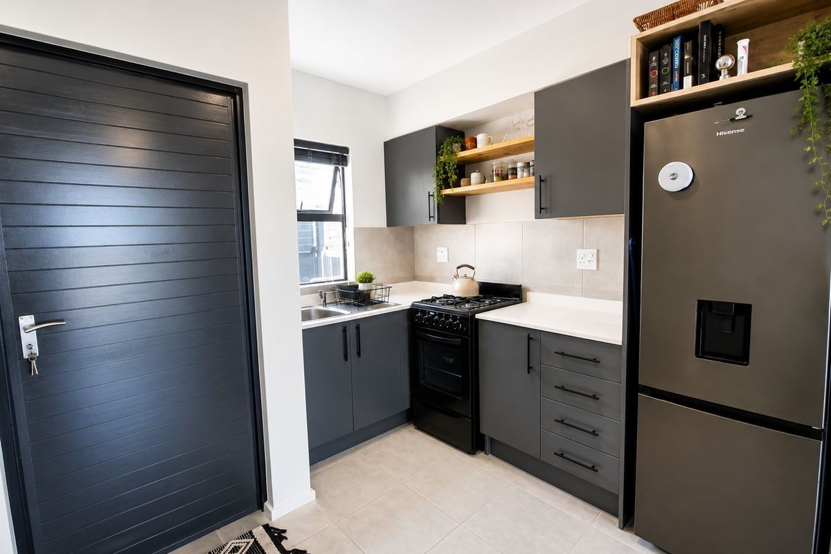 Modern kitchen featuring dark grey cabinetry, stone countertops, gas stove, oven, and open shelving, complemented by neutral floor tiles.