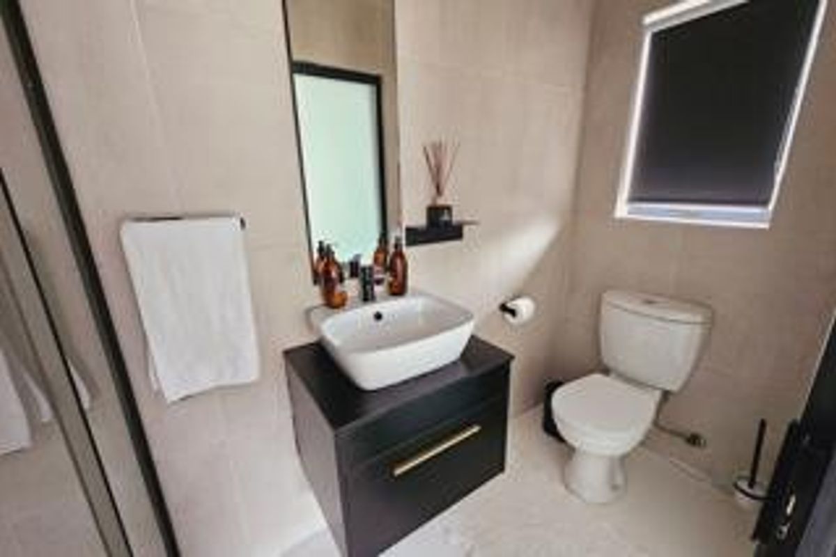 Modern bathroom featuring a floating vanity with a vessel sink, neutral wall tiling, and a clean, contemporary layout.
