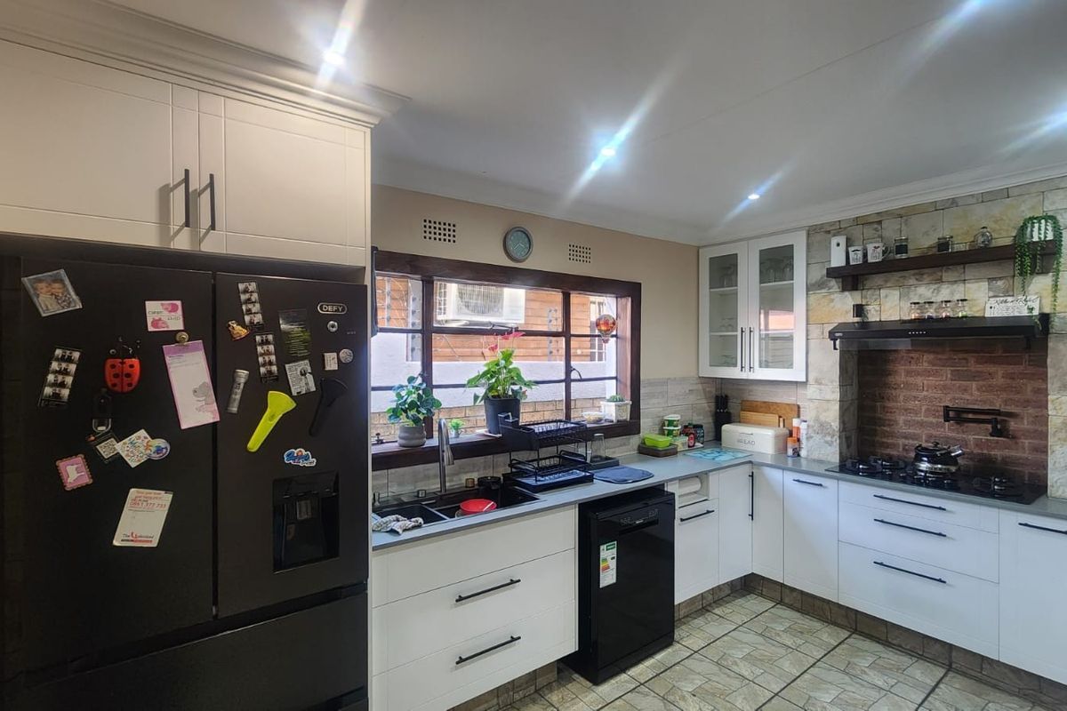 A well-appointed kitchen featuring white cabinetry, stone-cladding and brick accents, a gas hob, and integrated sink area with tiled flooring.