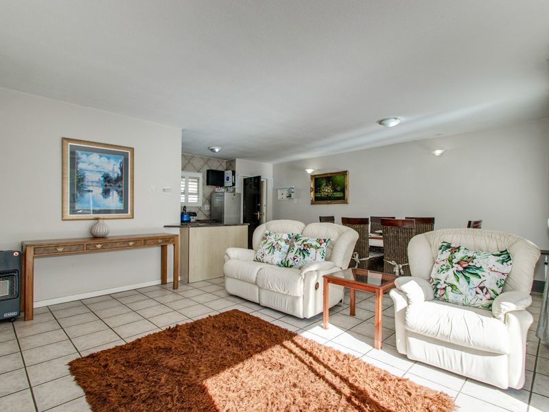 Open plan living and dining area featuring tiled flooring and a compact kitchen space with built-in cabinetry.