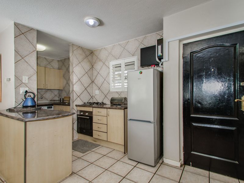 Compact kitchen featuring built-in cabinetry, granite countertops, gas hob, under-counter oven, and tiled flooring with a neutral splashback.