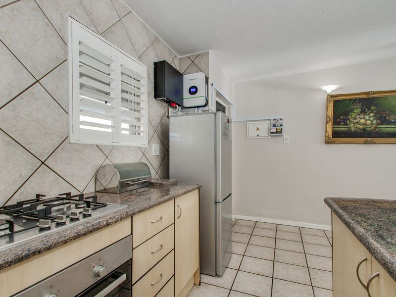 Functional kitchen featuring granite countertops, gas hob, built-in oven, and tiled finishes, with an integrated inverter system installed.