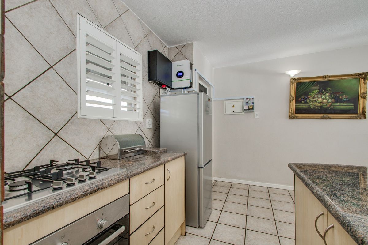 Functional kitchen featuring granite countertops, gas hob, built-in oven, and tiled finishes, with an integrated inverter system installed.