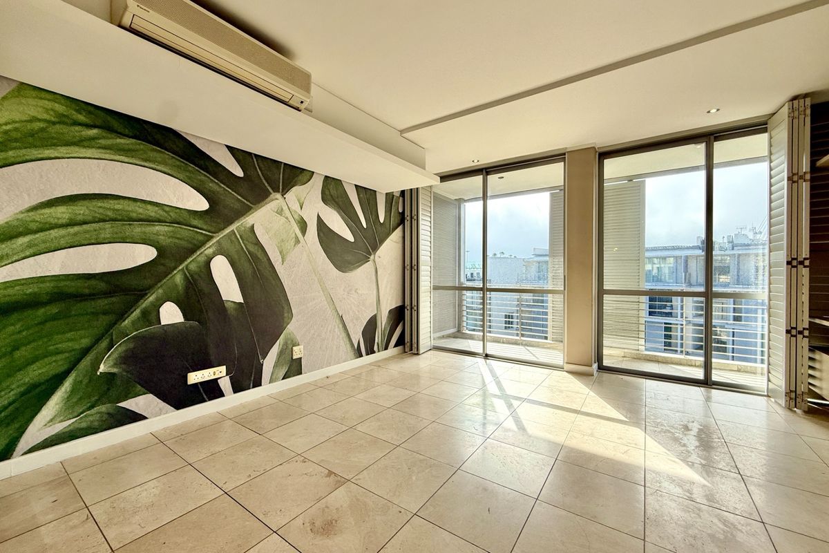 Bright and spacious living area featuring large sliding glass doors, tiled flooring, and a wall-mounted air conditioning unit.