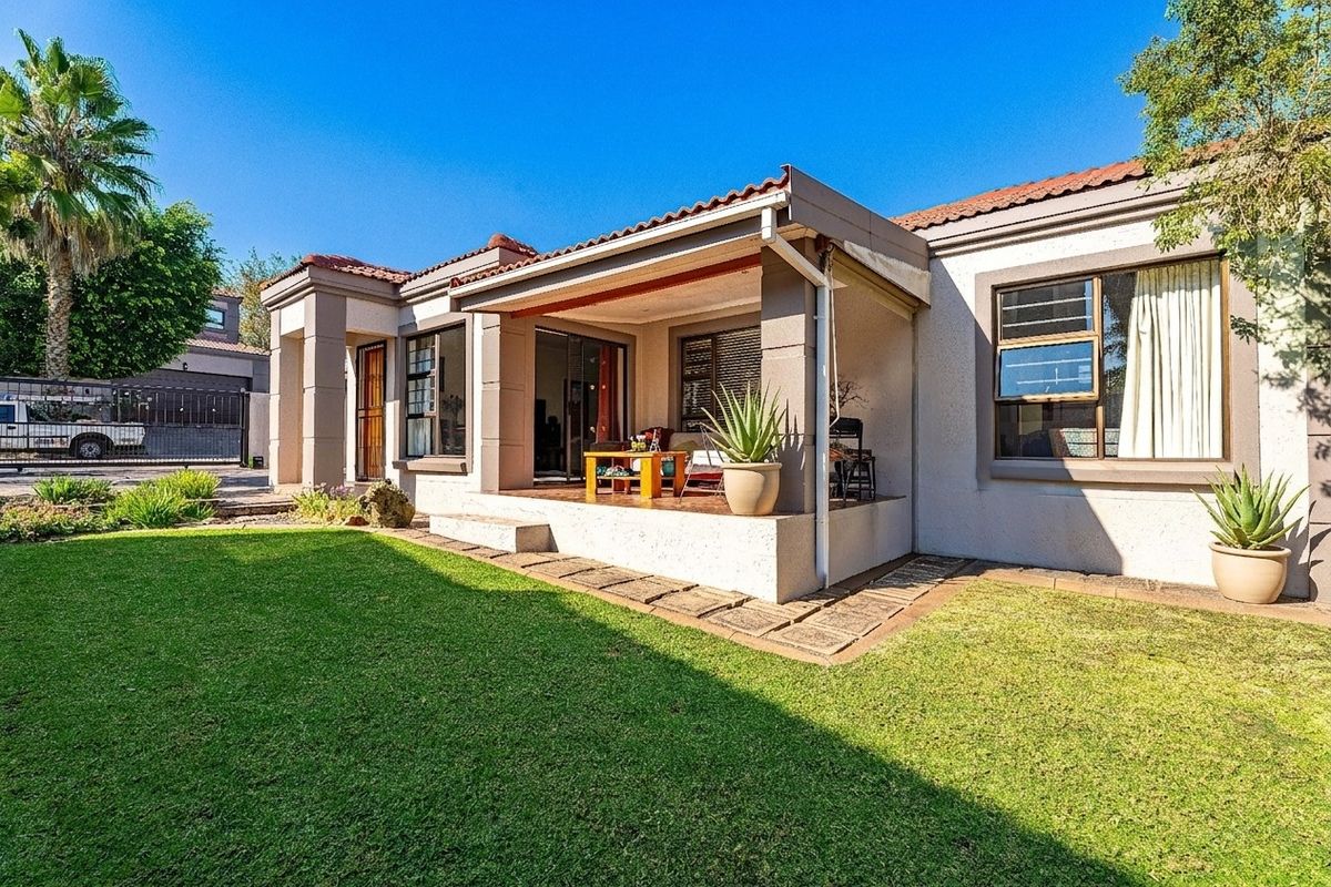 Rear view of the townhouse featuring a covered patio, sliding glass doors, and a well-maintained garden area.