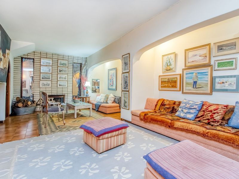 Spacious living room featuring a brick fireplace, arched architectural details, and tiled flooring, offering a comfortable and character-filled lounge area.