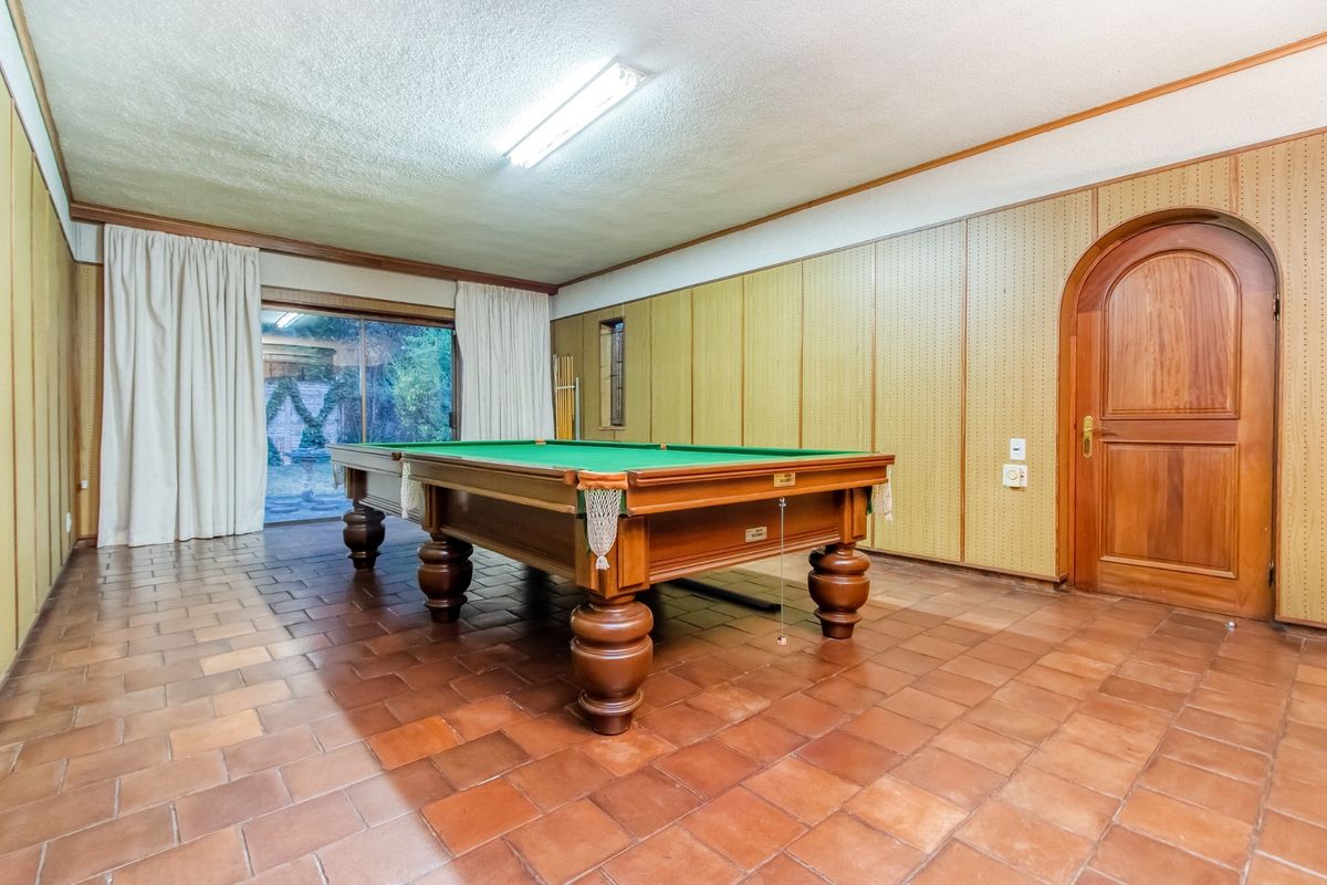 Spacious living area featuring terracotta tile flooring, an arched timber door, and sliding glass doors providing access to the outdoor area.