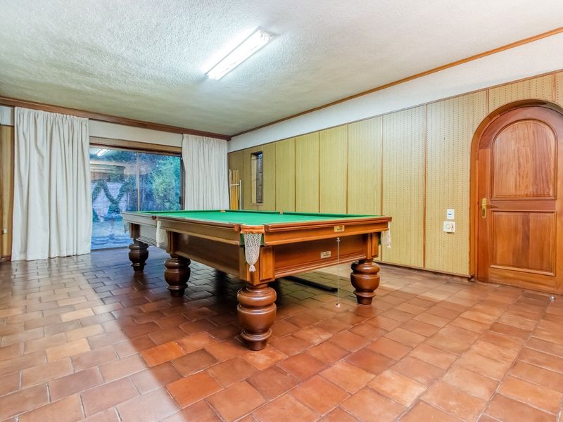 Spacious living area featuring terracotta tile flooring, an arched timber door, and sliding glass doors providing access to the outdoor area.