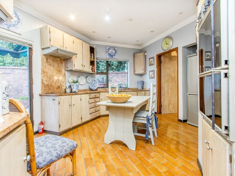 A functional kitchen featuring built-in cabinetry, a double wall oven, extractor fan, and durable tiled flooring with direct access to an outdoor patio area.
