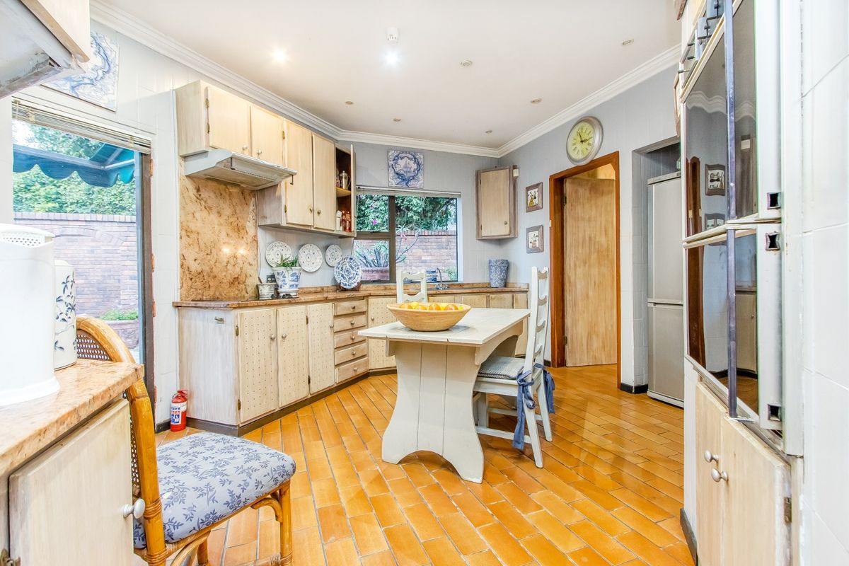 A functional kitchen featuring built-in cabinetry, a double wall oven, extractor fan, and durable tiled flooring with direct access to an outdoor patio area.