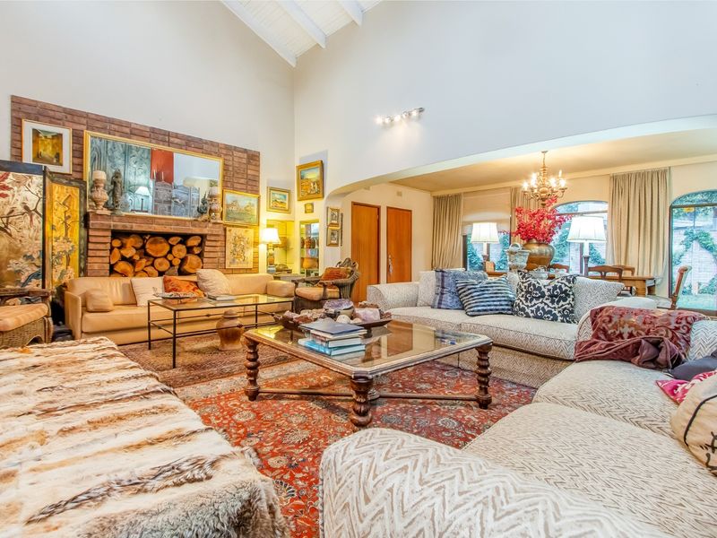 Spacious open-plan living area featuring a vaulted ceiling with exposed beams and a prominent brick fireplace, creating a warm and inviting atmosphere.