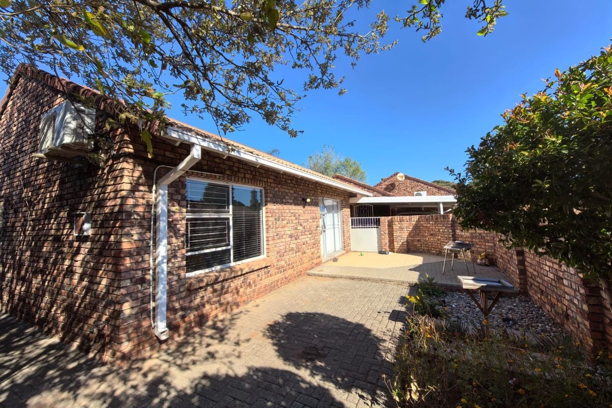 A private rear courtyard featuring face brick walls, paved patio area, and established garden surroundings, providing a low-maintenance outdoor living space.