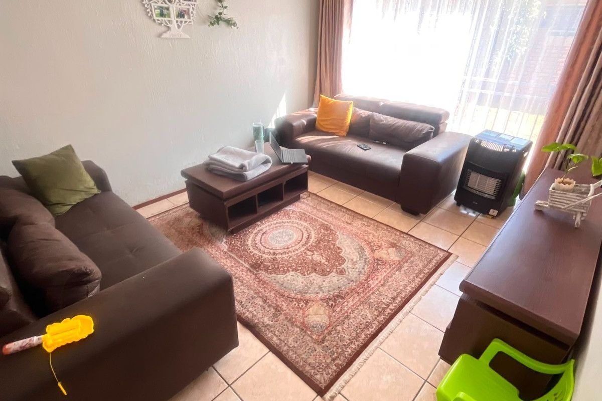 A living room featuring ceramic floor tiles and large windows with curtain tracks, providing a functional and comfortable space.
