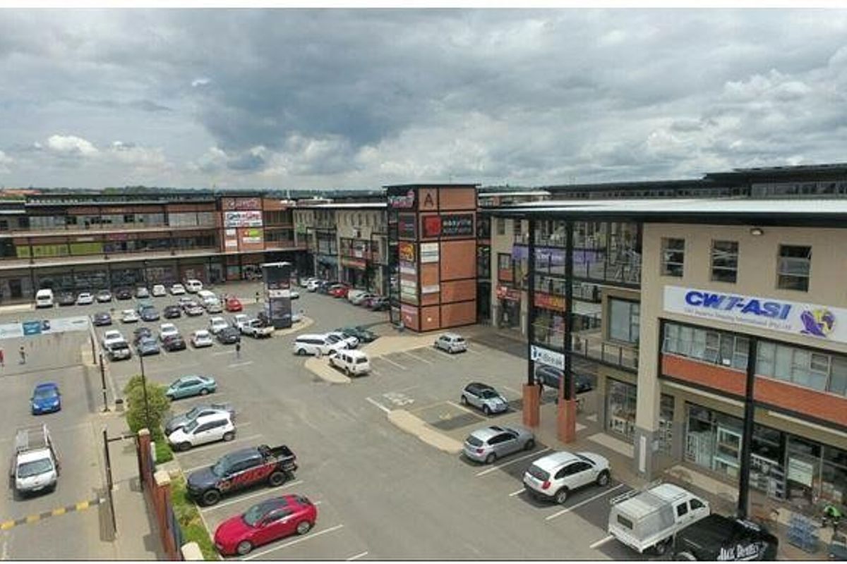 Aerial view of a multi-level commercial office complex featuring extensive paved parking, modern building facades, and prominent commercial signage.