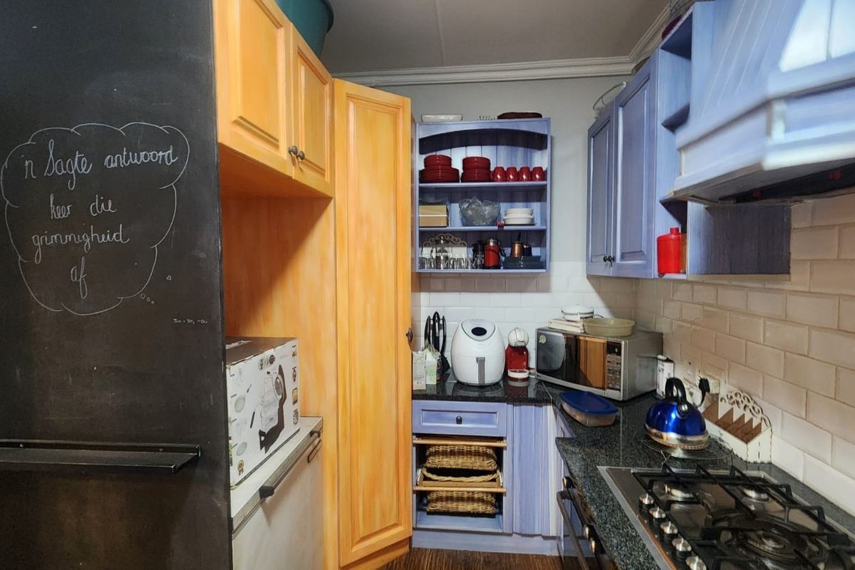 A functional kitchen featuring granite countertops, a gas hob, subway tile backsplash, and a mix of painted wooden cabinetry.