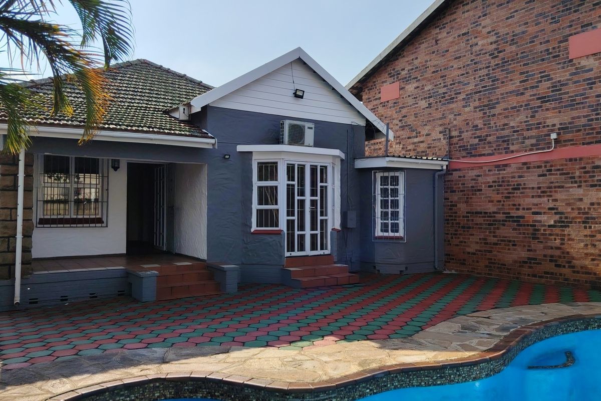 Rear exterior view of the townhouse featuring a paved patio area, swimming pool, and direct access to the living space via french doors.
