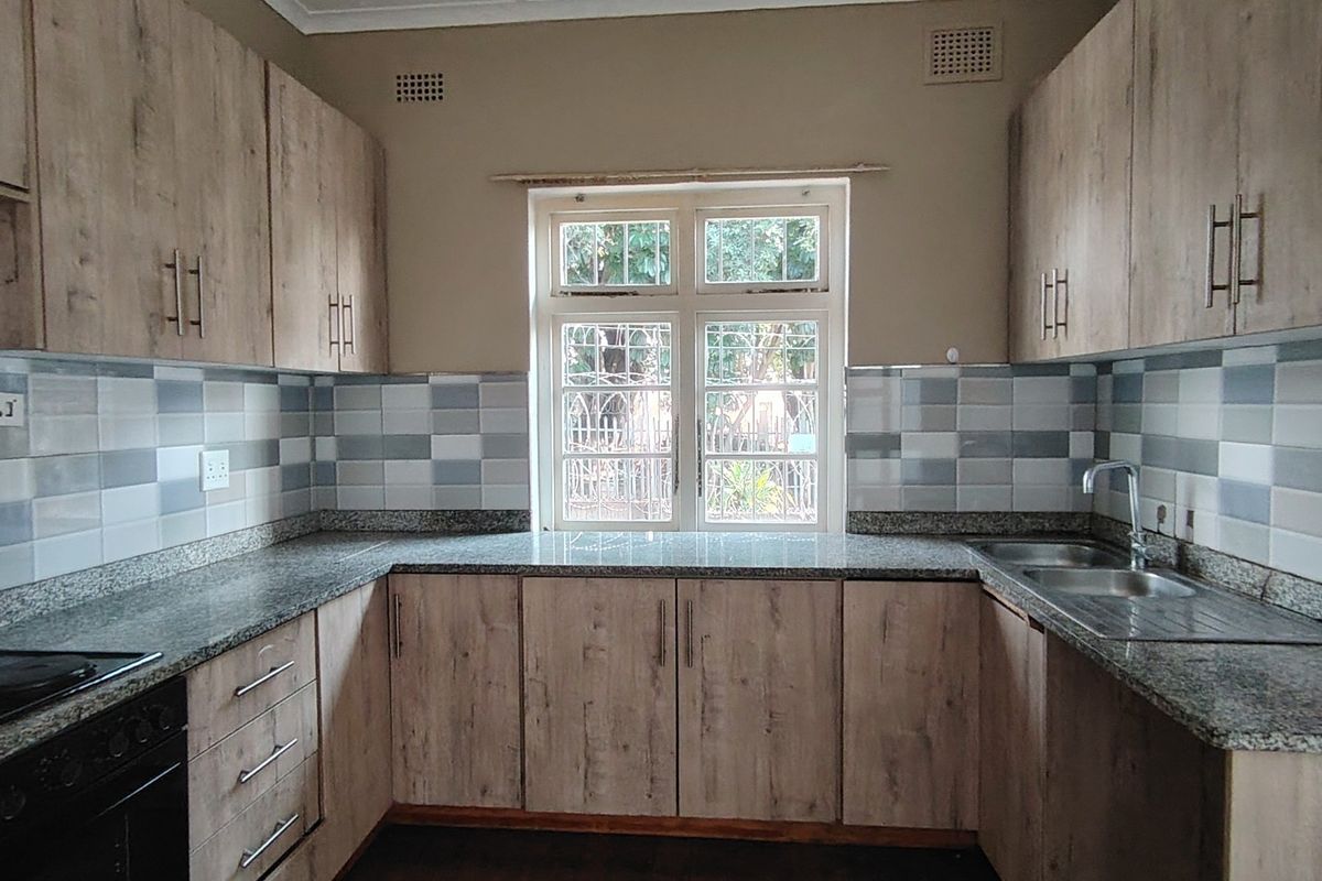 A clean and functional kitchen featuring wood-look cabinetry, granite countertops, a tiled backsplash, and a built-in oven with hob.
