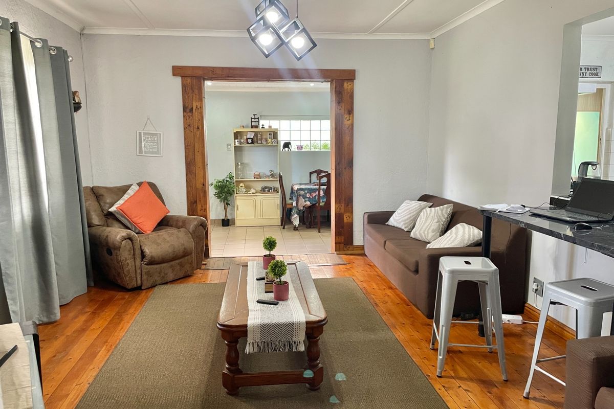 A living room featuring polished timber flooring, a distinctive exposed timber doorway leading to an adjacent room, and a breakfast bar area.