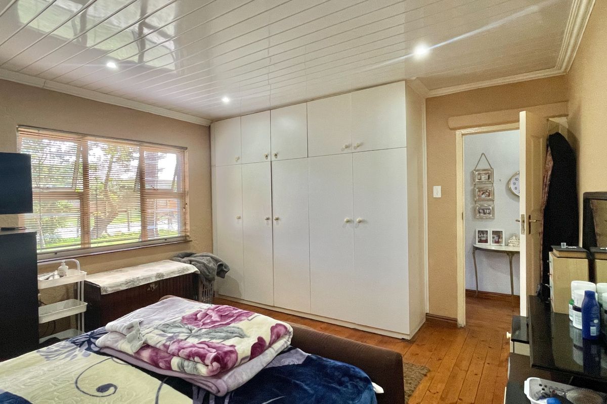 A bedroom featuring built-in cupboards, polished wooden flooring, and recessed ceiling lighting, offering a functional and well-maintained living space.