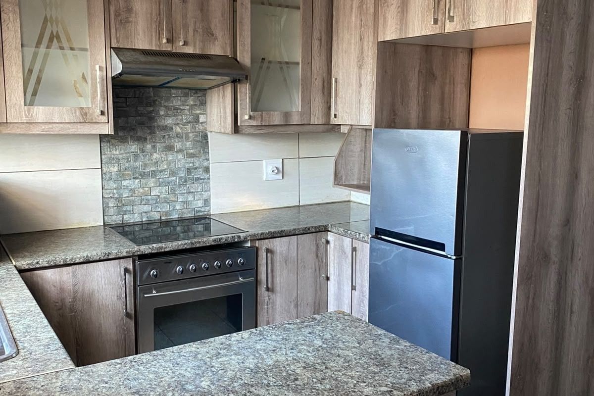 A functional kitchen featuring wood-look cabinetry, granite countertops, a tiled backsplash, and a built-in electric stove with an extractor fan.