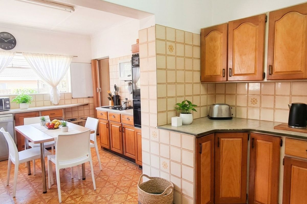 A functional kitchen featuring wooden cabinetry, tiled backsplash, and integrated appliances, offering a traditional layout with an adjacent dining area.
