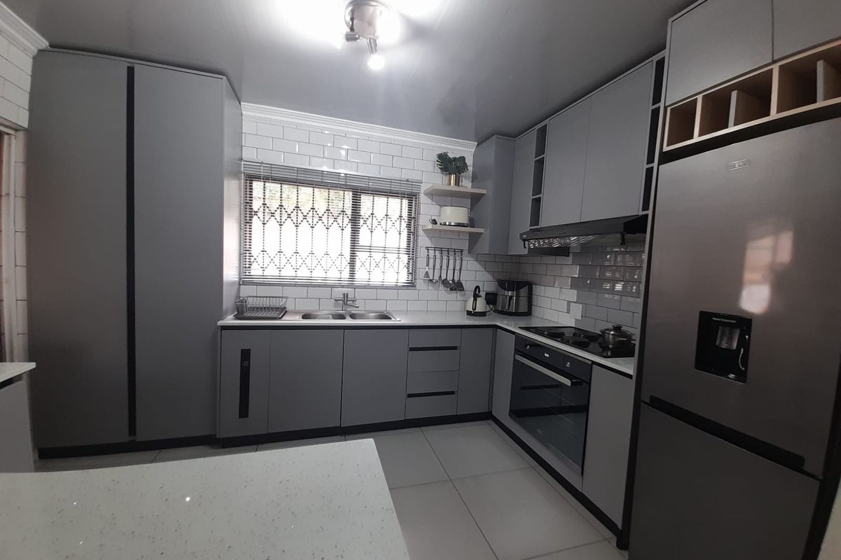Modern kitchen featuring sleek grey cabinetry, quartz countertops, subway tile backsplash, and integrated appliances, offering a clean and contemporary cooking space.