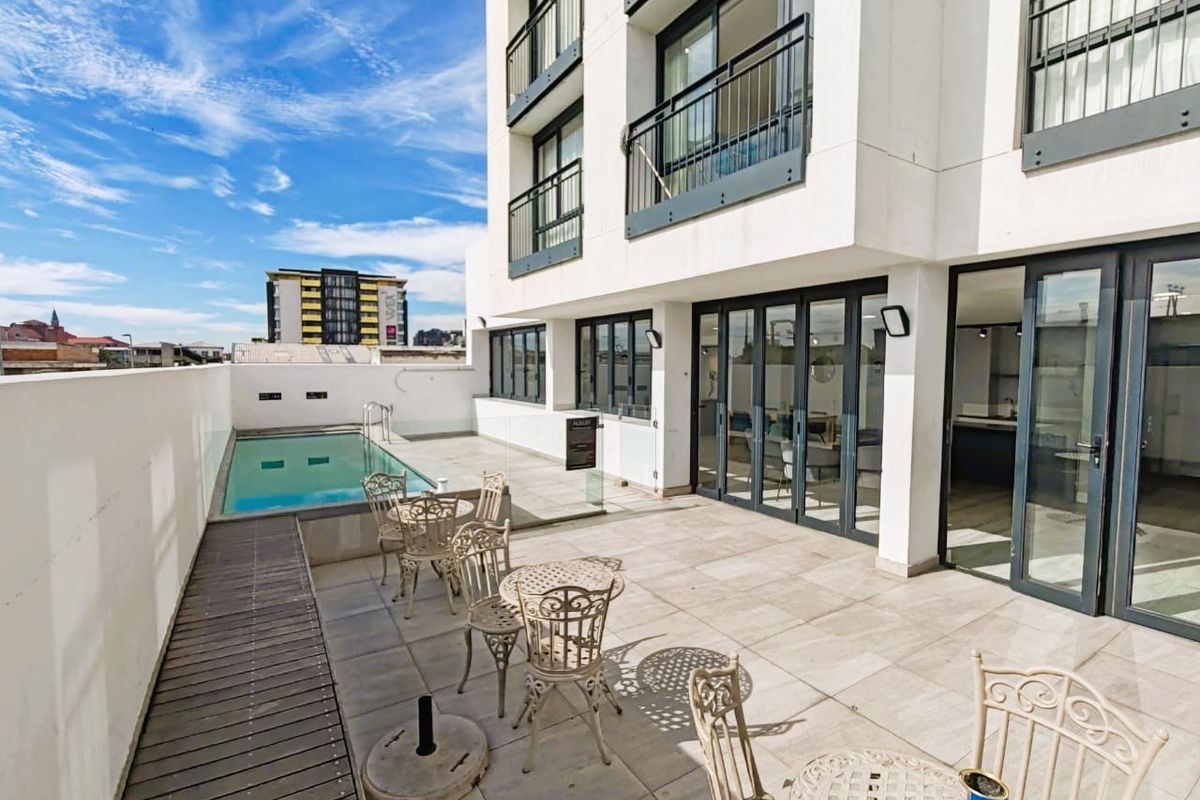 Spacious apartment terrace featuring a private swimming pool, tiled flooring, glass balustrades, and direct access to the interior living space via sliding doors.