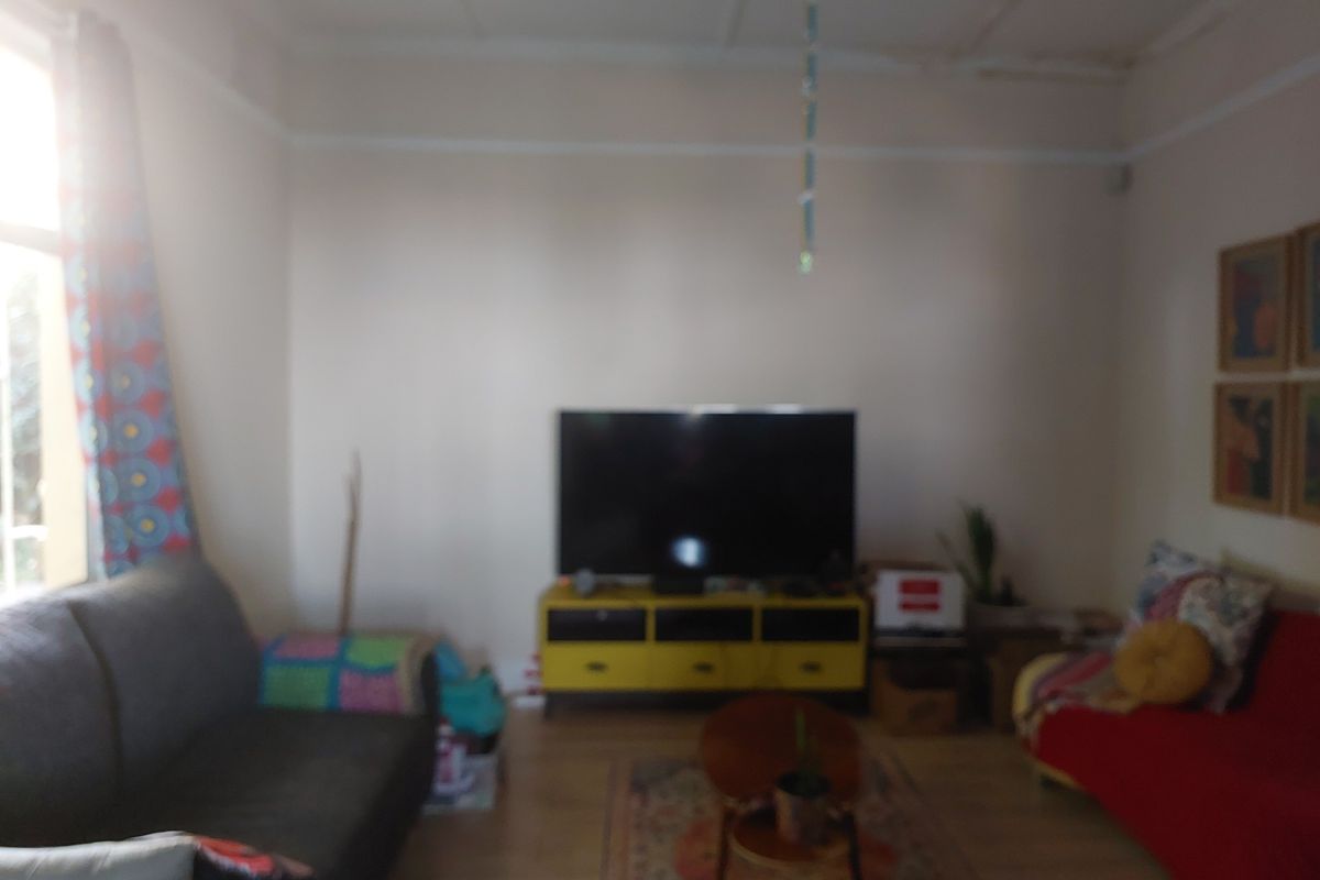 A living room area featuring standard wall finishes and flooring, currently furnished with seating and media equipment.