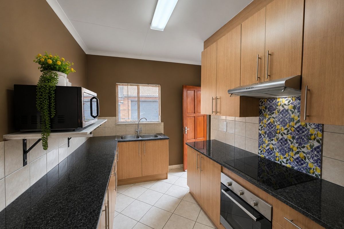 A functional kitchen featuring laminate cabinetry, granite countertops, built-in oven, ceramic hob, and a decorative tiled splashback.