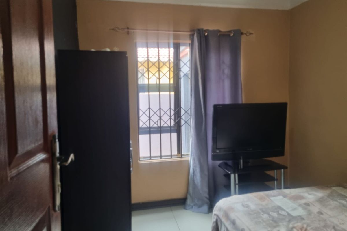 A bedroom featuring tiled flooring and a window fitted with security bars.