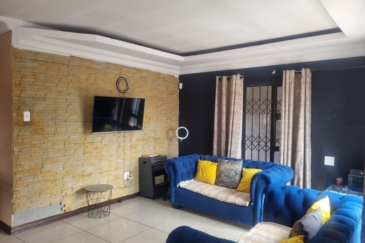 Living room featuring a textured stacked stone accent wall, recessed ceiling detail, and large format floor tiles.