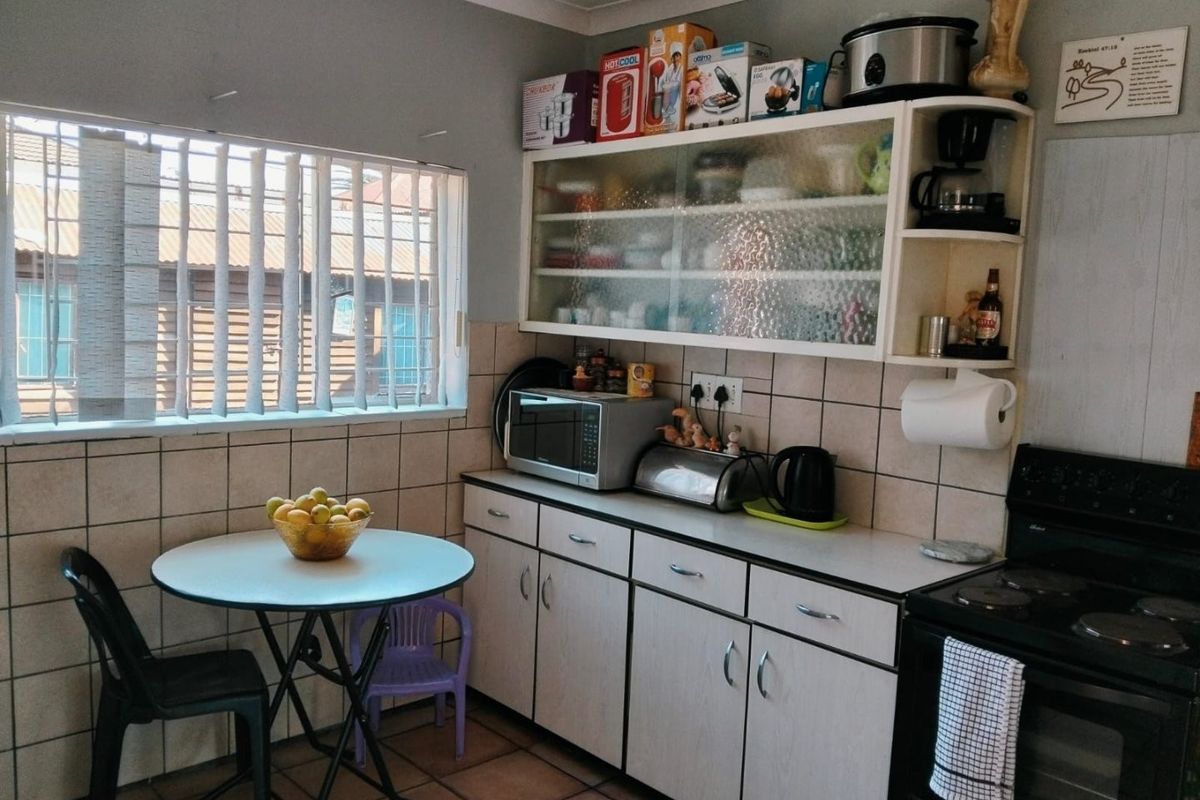 A functional kitchen featuring built-in cabinetry, tiled backsplash, tiled flooring, and an integrated electric stove with ample storage space.