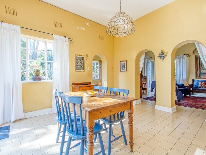 Dining room featuring tiled flooring, arched doorways, and steel-framed windows, with visible wall cracks requiring maintenance.