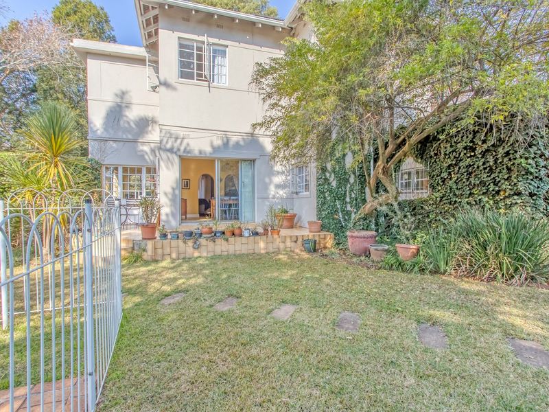 Rear view of the property featuring a tiled patio, sliding door access, and a private garden with established greenery.