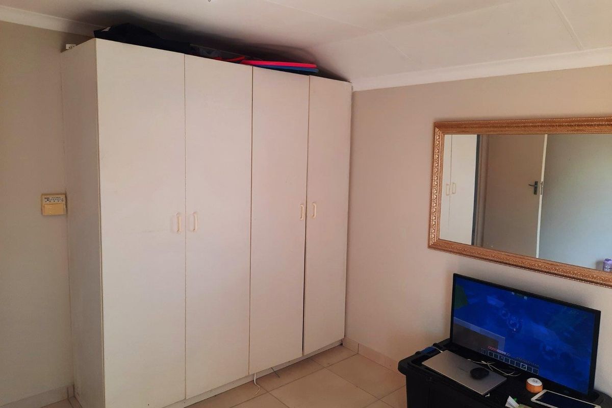 A bedroom featuring a large white built-in wardrobe, tiled flooring, and coved ceiling details.