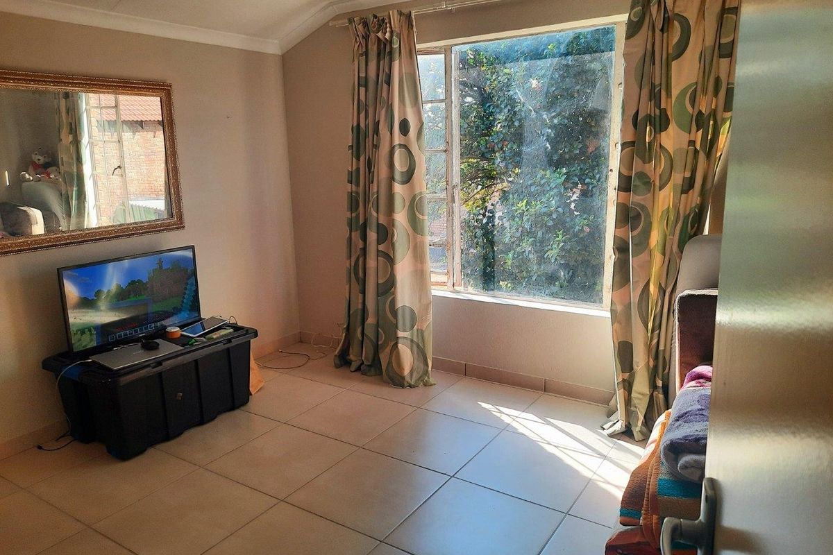 A living room featuring tiled flooring, coved ceilings, and a large window providing natural light.
